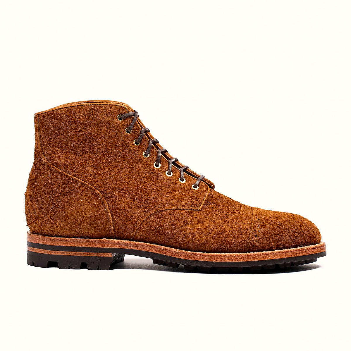 Bronze perforated cap toe service boot in rough suede, set on a lug rubber outsole